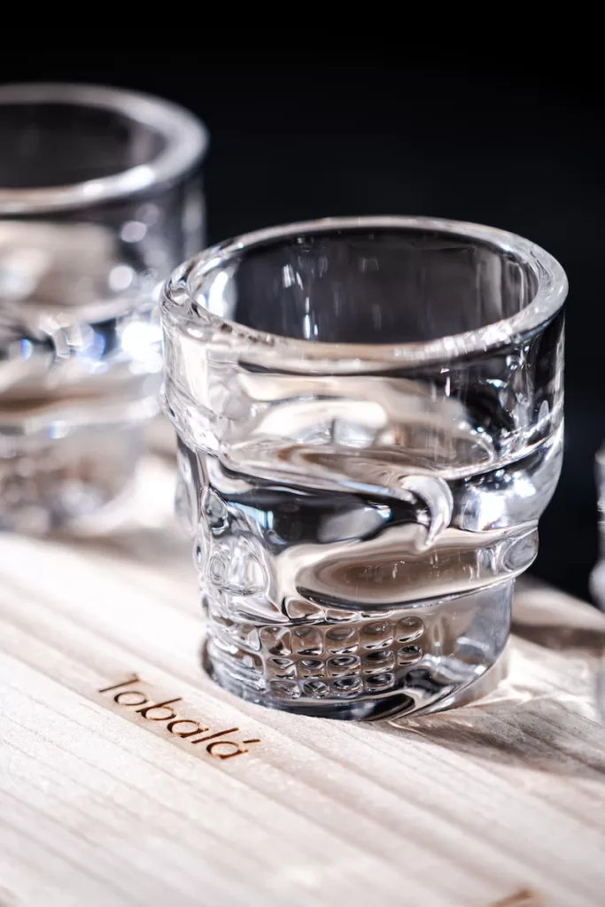 two shot glasses sitting on top of a wooden table and Tequila Tasting Tlaquepaque