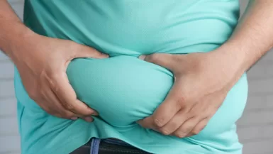 a man holding his stomach with his hands - say fat in spanish