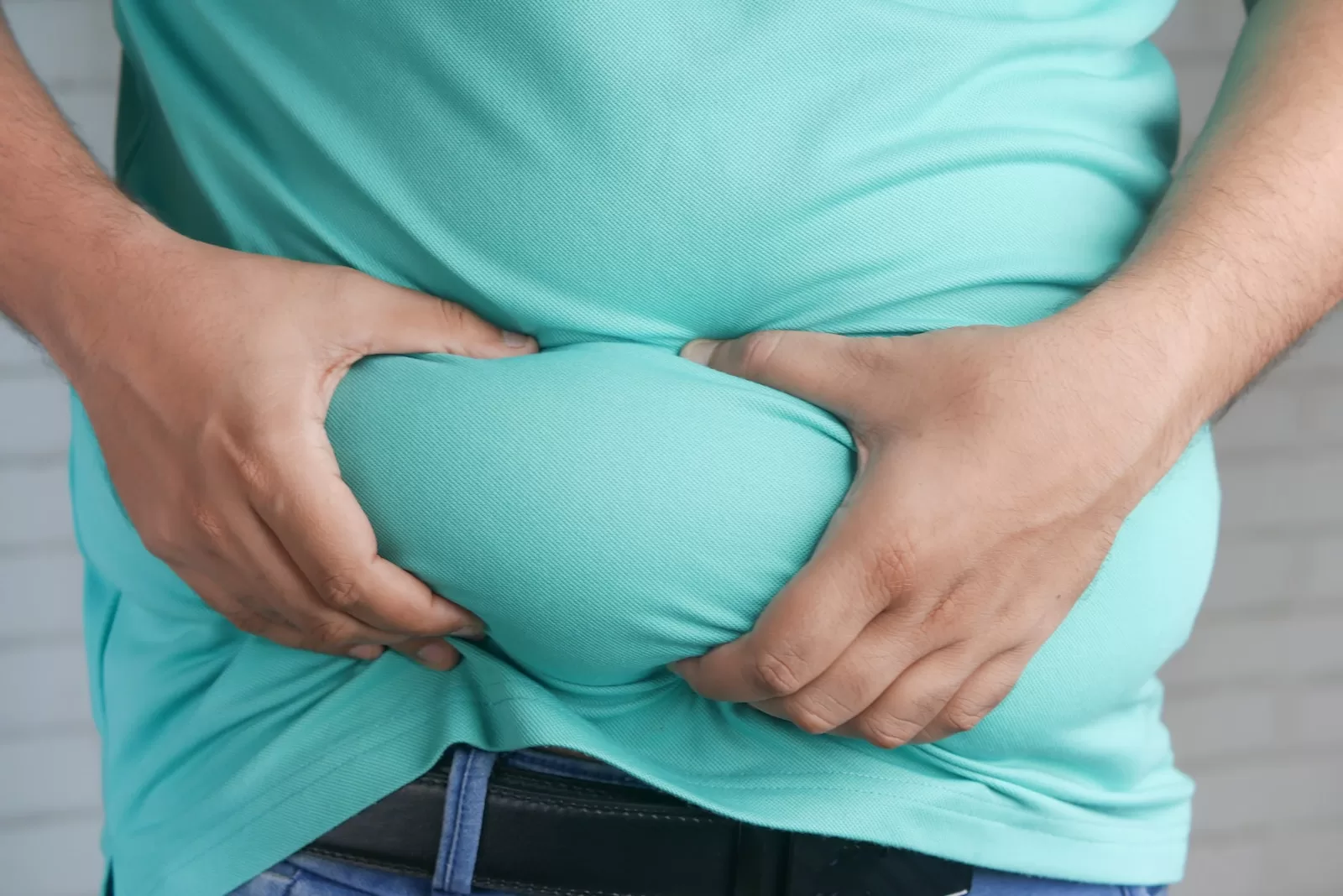 a man holding his stomach with his hands - say fat in spanish