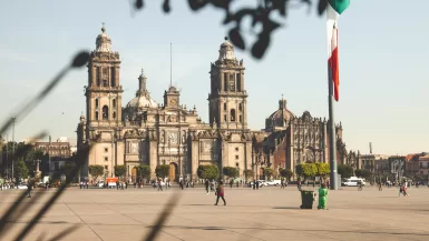 people walking on sidewalk near brown concrete building during daytime - pros and cons of living in Mexico City