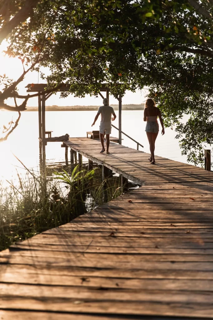 Bacalar  couple of people walking across a wooden bridge