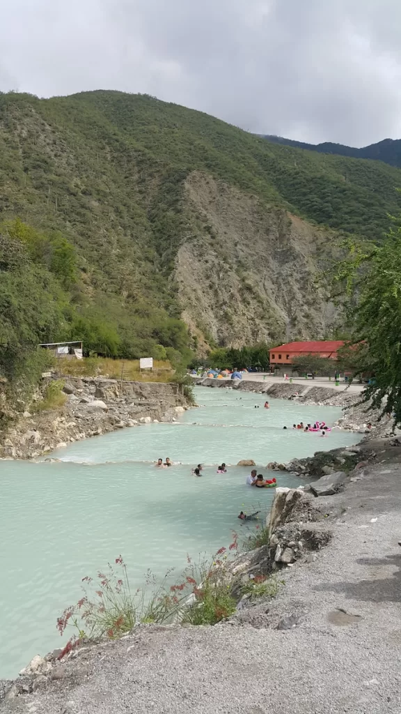 people are swimming in a river near a mountain Tolantongo Hot Springs