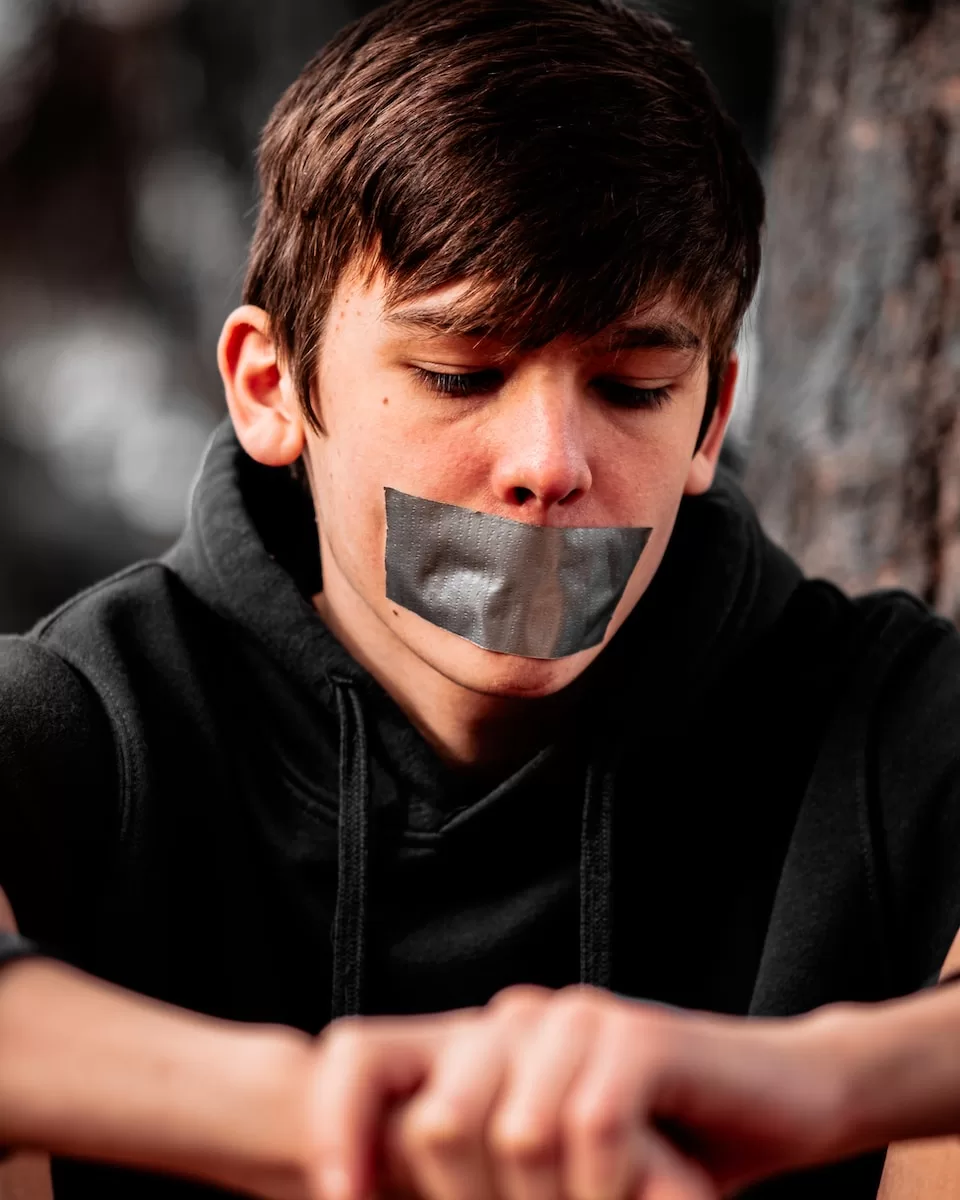 man in black hoodie wearing silver framed eyeglasses and shut up in spanish slang