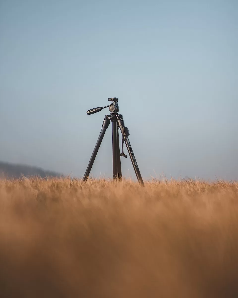 black camera and travel tripod on brown grass field during daytime