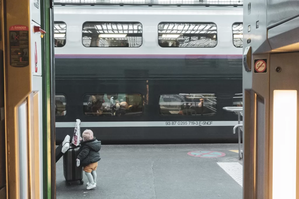 a woman standing next to a train at a train station paris to nice train