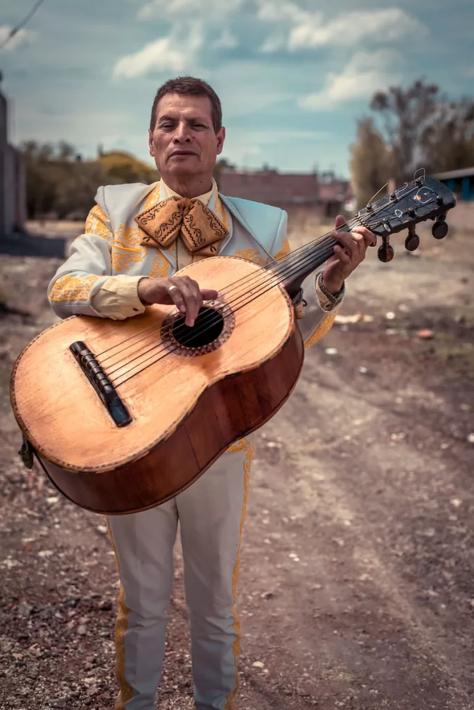 standing man holding brown sting musical guitar during daytime Mariachi in guadalajara