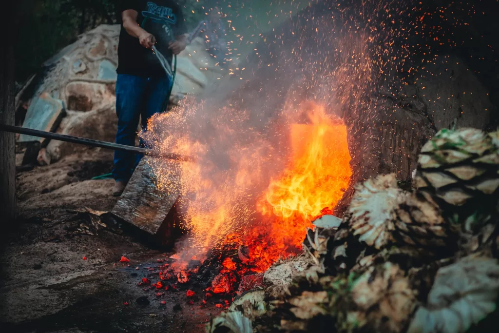 a man standing next to a pile of fire mezcal vs tequila