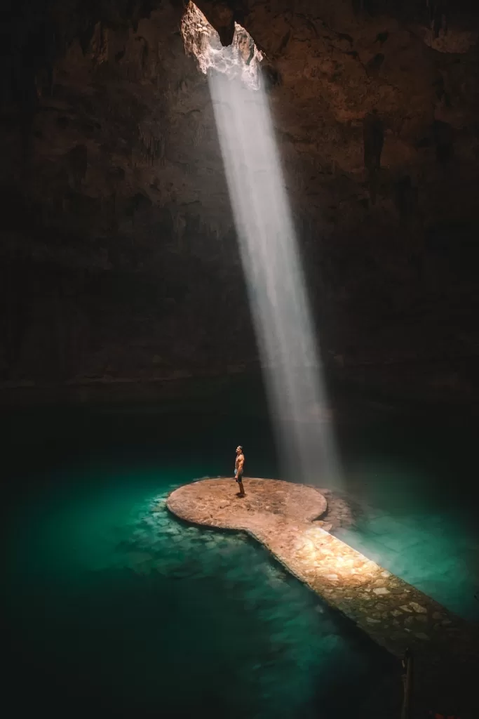 person standing on brown platform under water lake Cenote Suytun