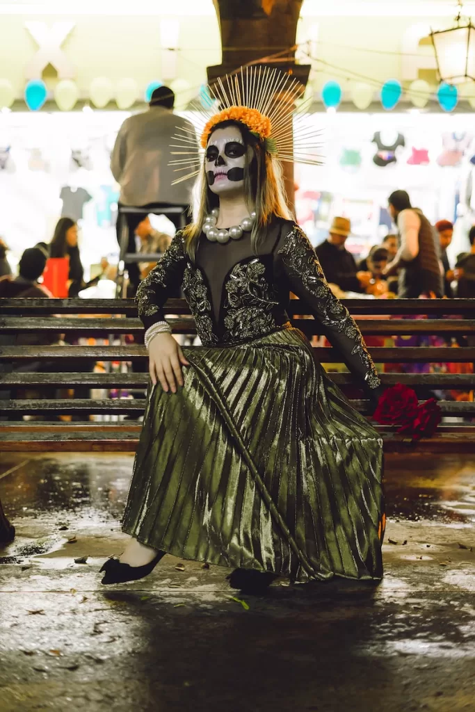 a woman in a skeleton mask and dress sitting on a bench day of the dead Tlaquepaque Jal.