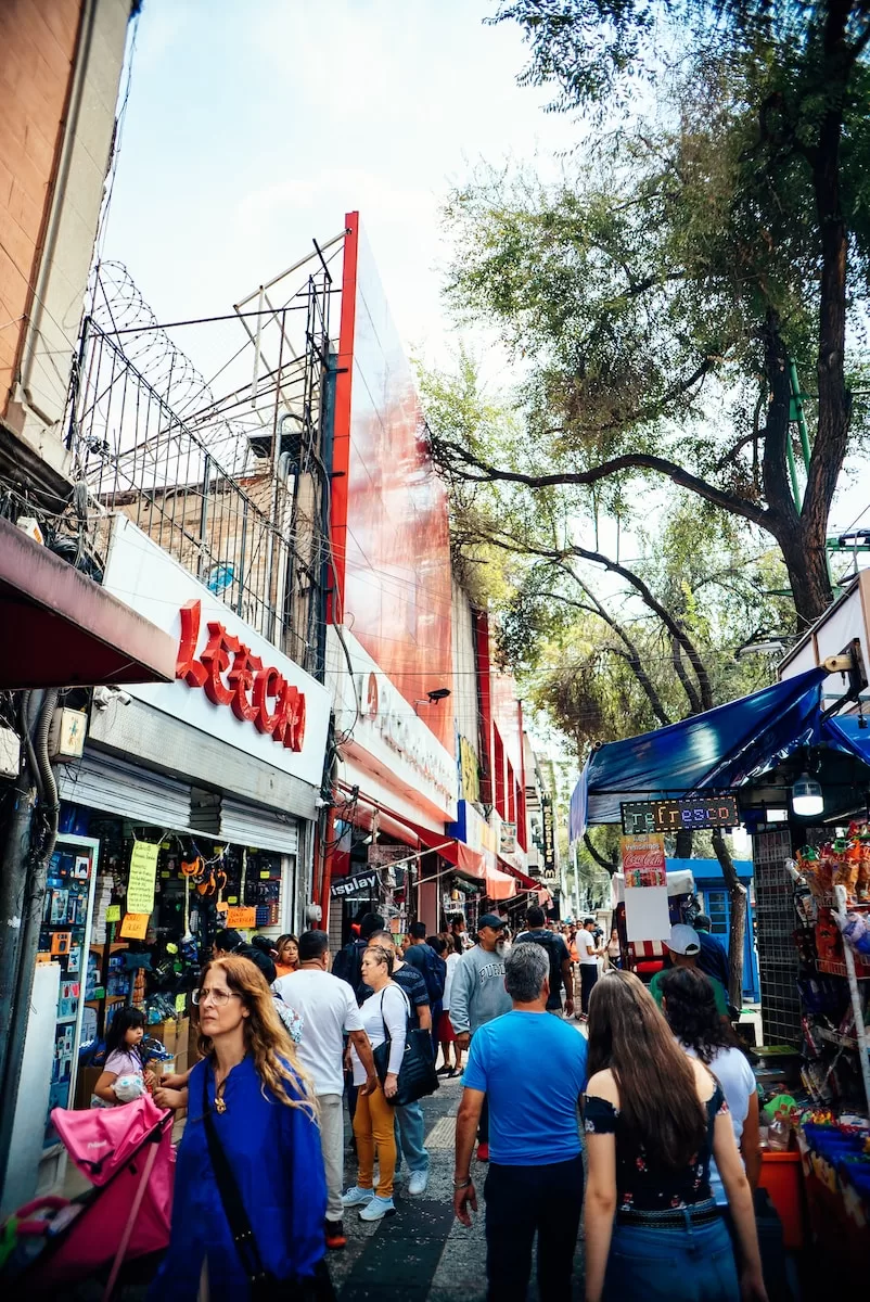 a group of people walking down a street next to stores on 5th Avenue Playa Del Carmen