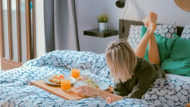 woman lying on bed white holding board of travel essentials for women