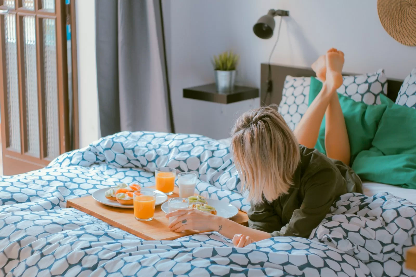 woman lying on bed white holding board of travel essentials for women