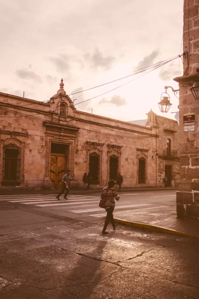a person walking down a street in front of a building in Morelia Mx