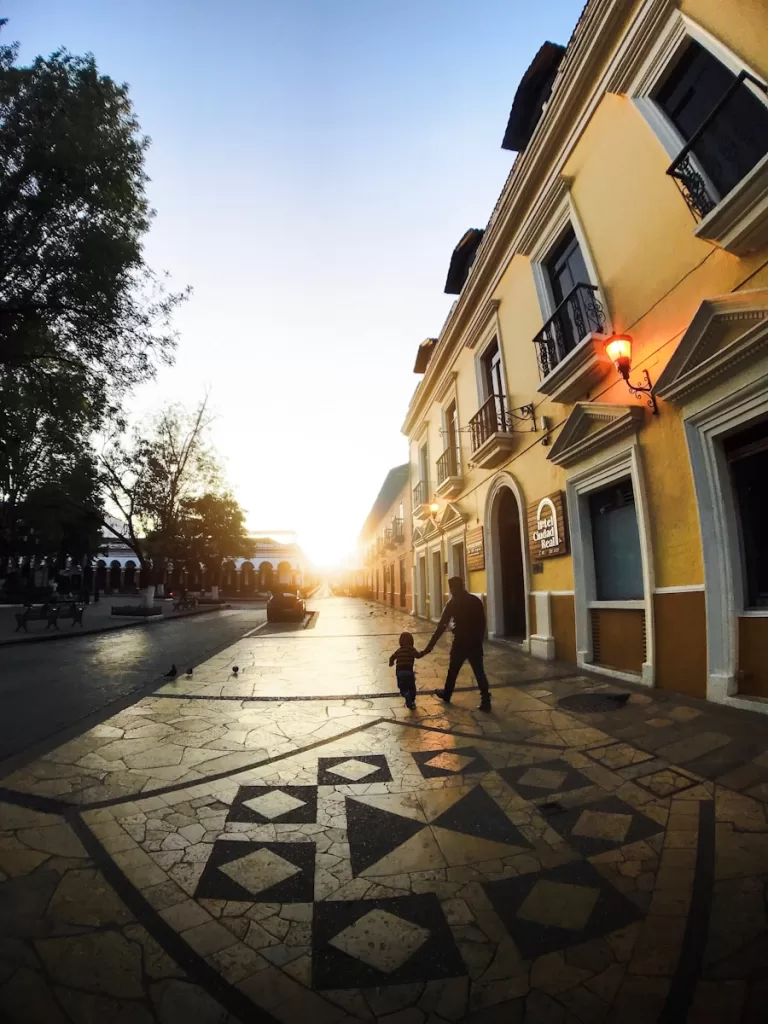 people walking on street during daytime vibrant street-level view of San Cristóbal de las Casas, capturing the essence of its cobblestone streets, colonial architecture, and the lively atmosphere of its markets and cafes in chiapas