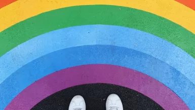 person in white pants and white sneakers standing on black and red carpet