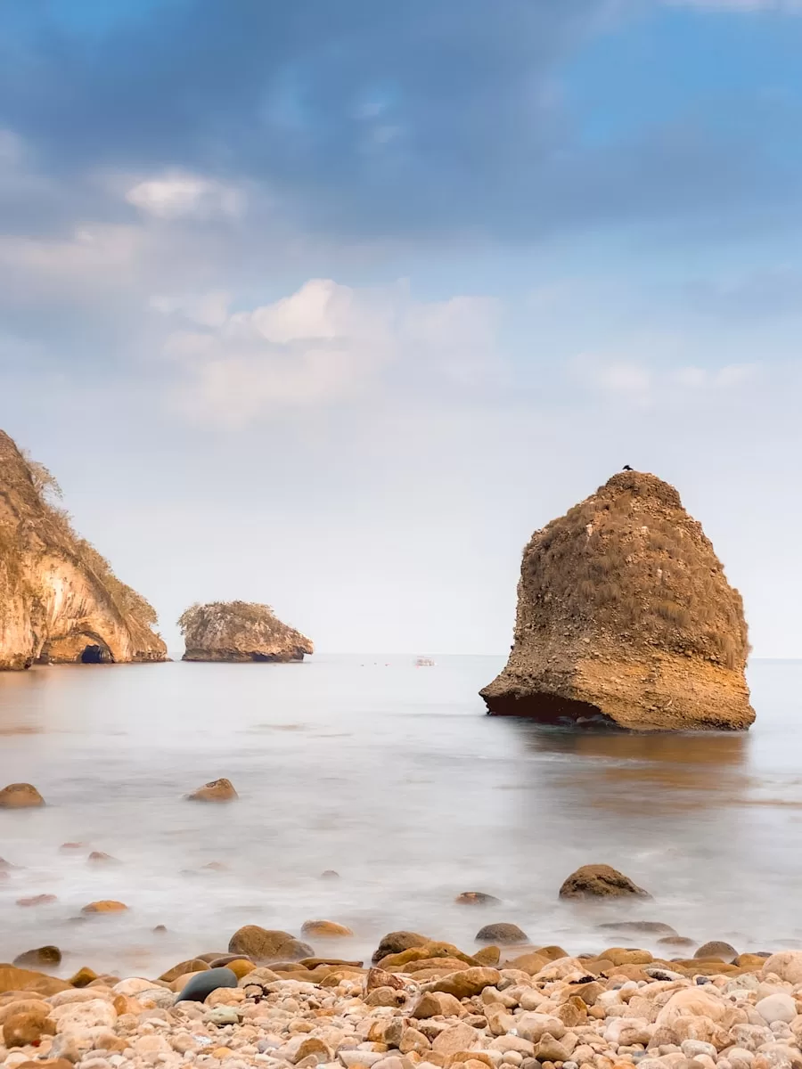 a rocky beach with two large rocks sticking out of the water in Mismaloya