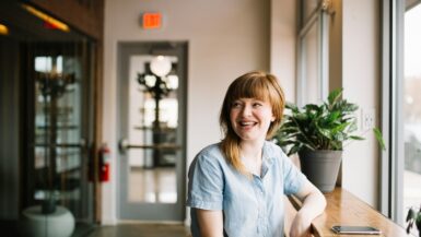 woman sitting in front of brown wooden table of a travel CNA job