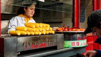 A woman standing in front of a food stand Local Cuisine