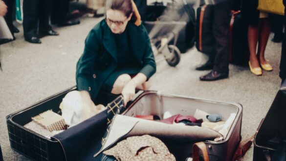 A woman sitting in an open suitcase on the ground