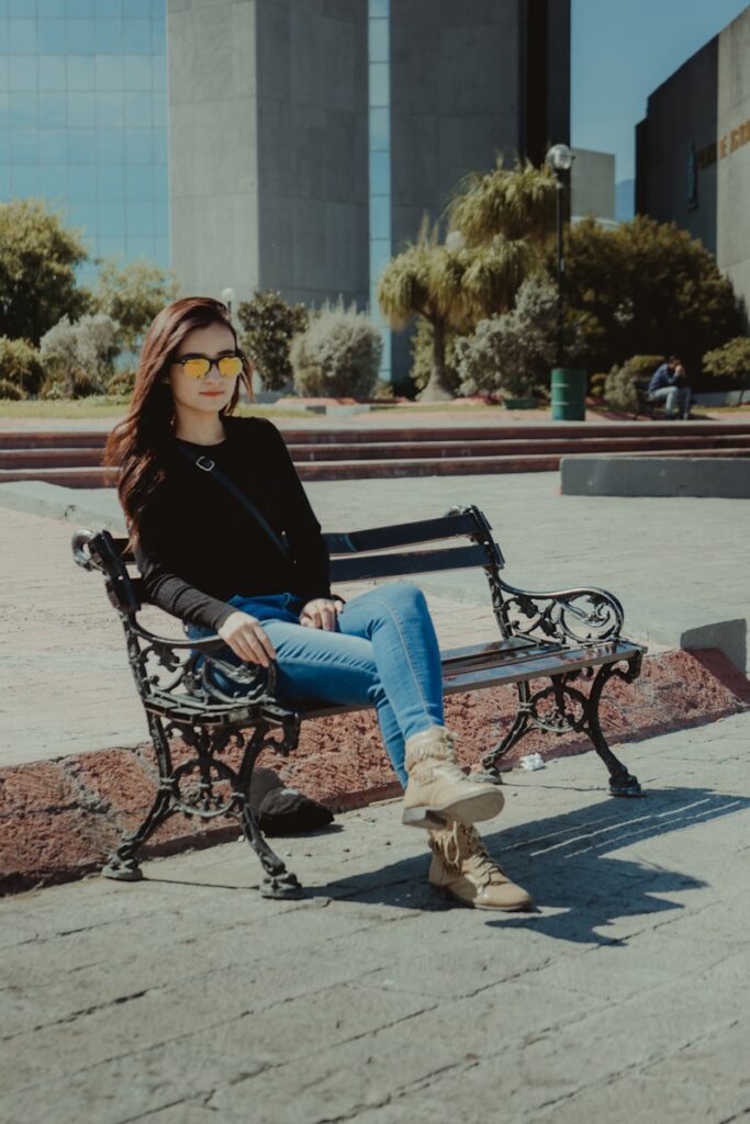 woman in black long sleeve shirt and blue denim jeans sitting on black metal bench during Macroplaza