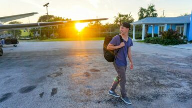 smiling man walking while looking side view Travel Hacks