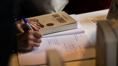 person writing on notebook near book what are you doing in spanish