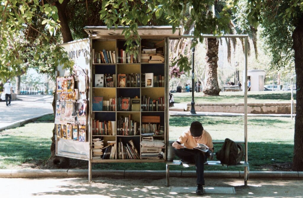 boy sitting on bench beside bookshelf Fundidora Park