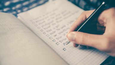 person writing bucket list on book Packing List