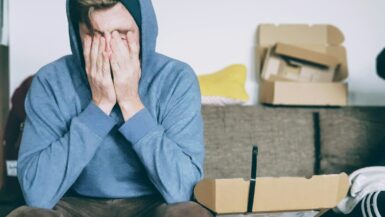 man covering face with both hands while sitting on bench Travel Anxiety