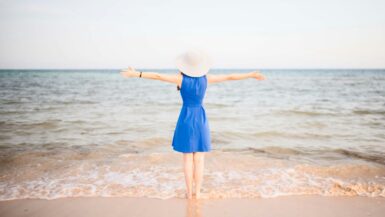 a woman in a blue dress standing on a beach Beach Vacation