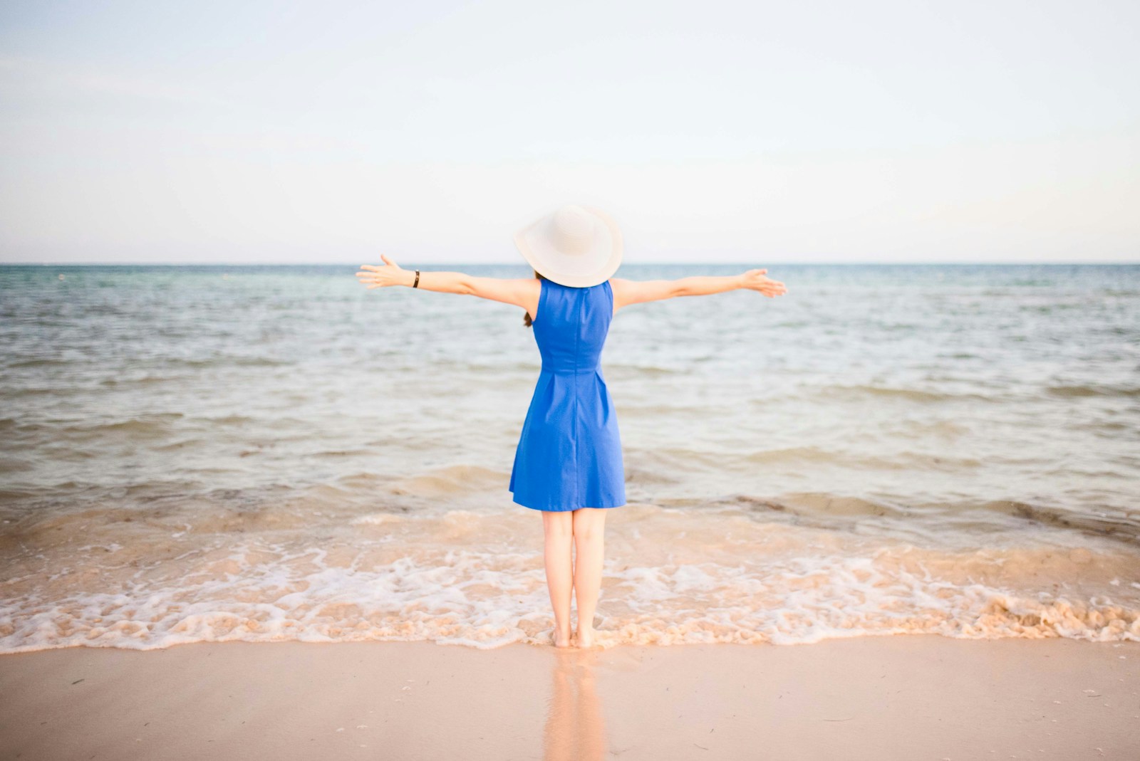 a woman in a blue dress standing on a beach Beach Vacation