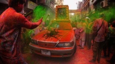 a group of people standing around a red car Cultural Traditions