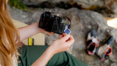 A woman sitting on a chair holding a camera journaling